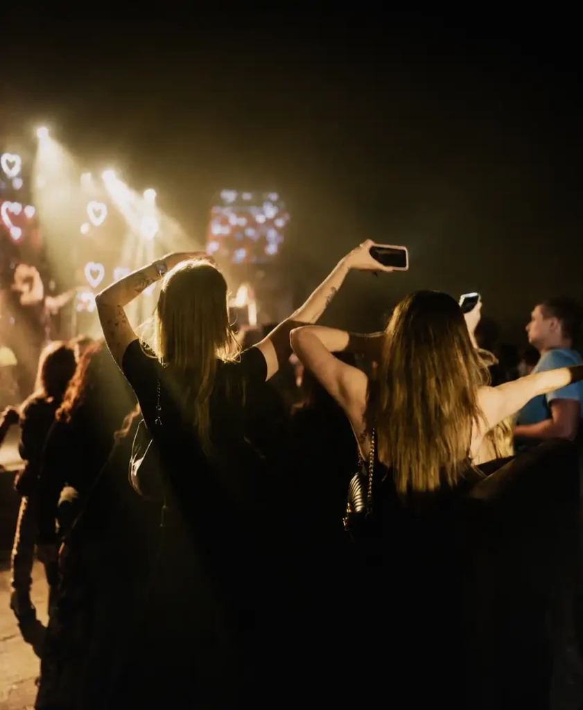 2 Frauen tanzen im Club mit Händen in der Luft und Lichtern